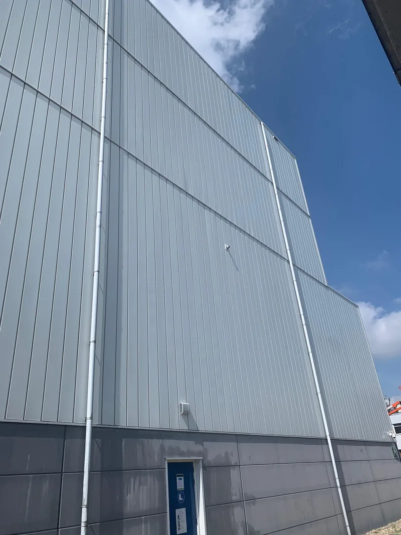 Lichte metalen gevelpanelen van een groot bedrijfspand na gevelreiniging